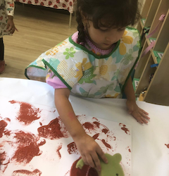 Alara helps to paint mud paint for our book week board.