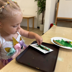 Ella painting her green colour monster with a leaf!