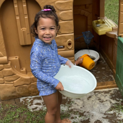 Alba carrying a tub of water to create muddy puddles. 