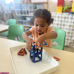 Amara carefully stacking the magnets to build a house . 