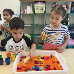 Mateo and Alba enjoying sensory bin with colours .