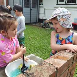 Girls enjoying the pretend cooking at water play.