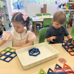 Klaudia and Leo building a train and train station using magnet connectors. 