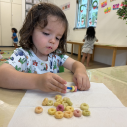 Cru threading cereal onto a pipe cleaner!