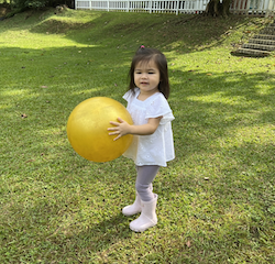 Ellie enjoying throwing and kicking the ball in the garden.